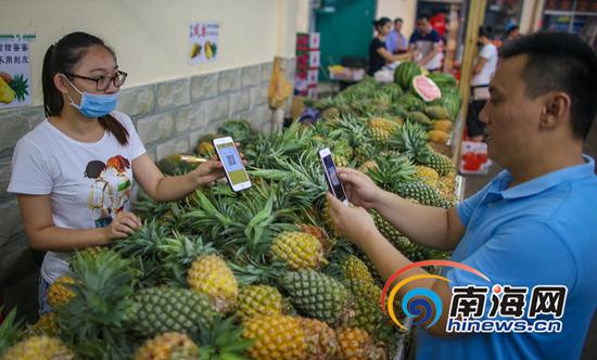 海口市民在菜市场买水果扫描二维码付款。海报集团全媒体中心记者 袁琛 摄